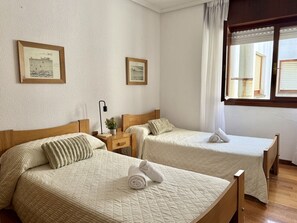 Ein Hotelzimmer mit zwei Betten, einem Nachttisch, einer Lampe und zwei gerahmten Bildern an der Wand.