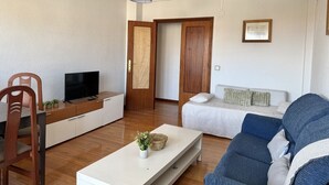 Ett vardagsrum med en TV, en soffa och en matplats med stolar.