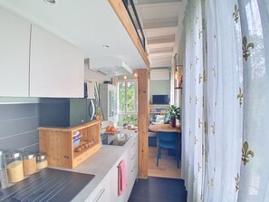 Eine moderne Küche mit Holzausstattung, einem eingebauten Herd und einem Essbereich mit einem blauen Stuhl.