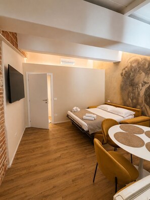 A compact hotel room with a bed, a small table, and a TV. - Pitti Suite 1 (Florence)