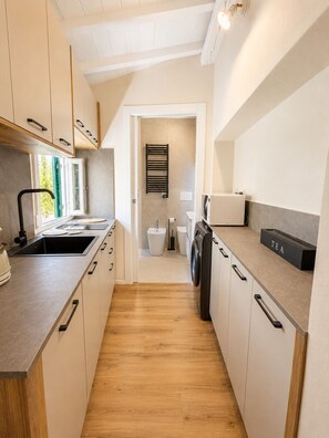 A modern kitchen with a built-in washing machine, a sink, and a countertop with a tea box. - Pitti Suite 1 (Florence)
