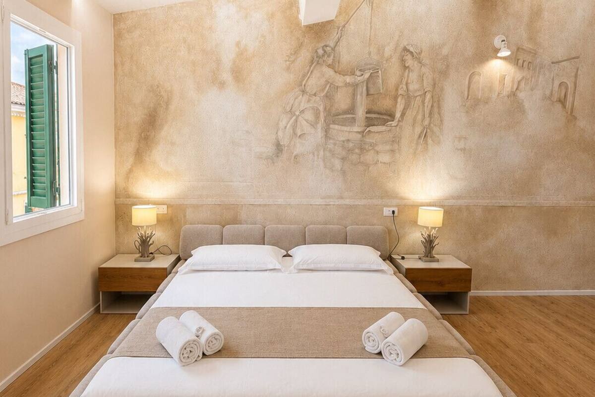 A large, modern bedroom with a long bed, wooden floors, and a mural on the wall.