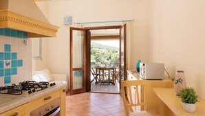 A kitchen with a stove, oven, and dining area with a table and chairs. - Casa Luna e Sole by Wonderful Italy (Budoni)