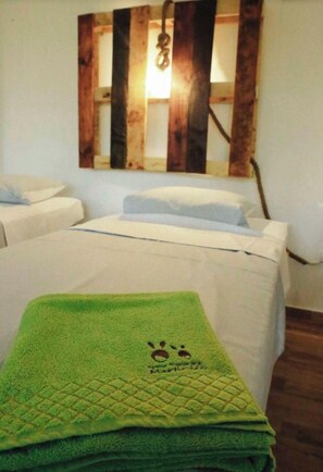 Una habitación con una cama, una toalla verde y una decoración de madera en la pared.