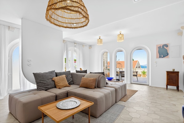 Ein modernes Wohnzimmer mit einem Ecksofa, einem Couchtisch aus Holz und einem großen Fenster mit Aussicht.