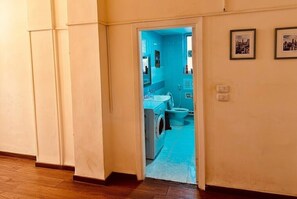 A hallway leading to a bathroom with a blue wall, a sink, and a toilet. - Spacious 6-bedroom apartment in peaceful Amman with AC (Amman)