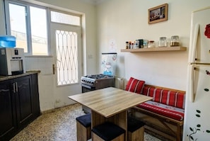 A compact kitchen with a gas stove, a refrigerator, a water dispenser, and a wooden table with benches. - Spacious 6-bedroom apartment in peaceful Amman with AC (Amman)