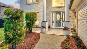 Et tosyltet hus med murstensfacade, en veranda og et stort vindue med dekorativt glasdesign.