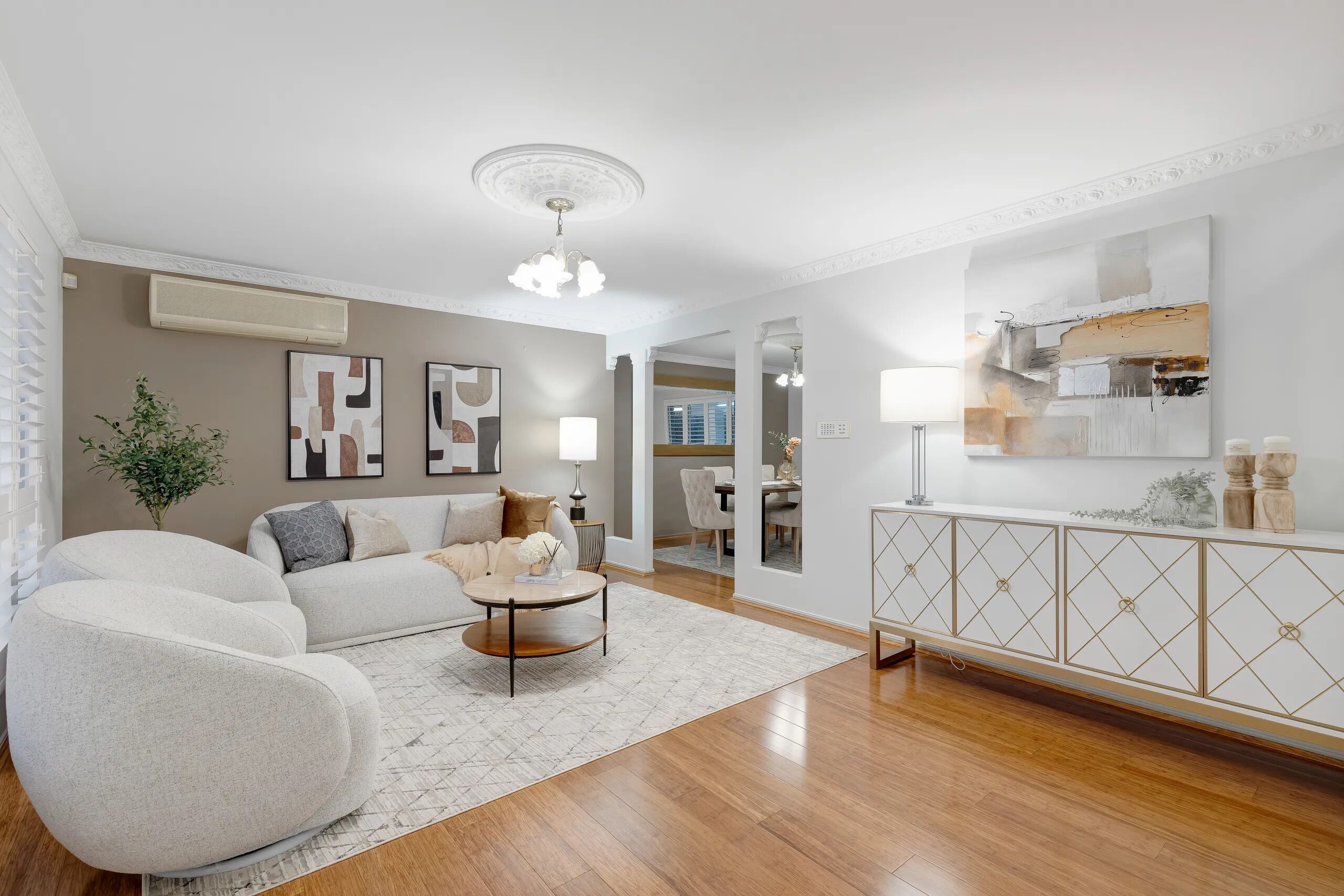 A modern living room with a sofa, armchair, coffee table, and a decorative cabinet.