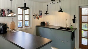 Una cocina con encimera negra, cafetera, tostadora y cuchillos colgados.