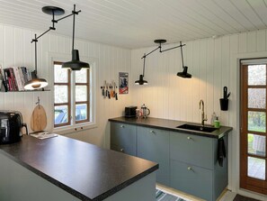 Eine Küche mit schwarzem Arbeitsplatz, einer Kaffeemaschine, einem Toaster und an der Wand hängenden Messern.