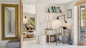 Una habitación con cama, escritorio, silla, estantería y espejo.