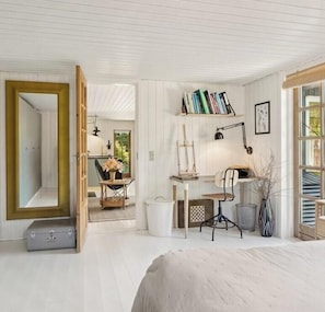 Ein Zimmer mit Bett, Schreibtisch, Stuhl, Bücherregal und Spiegel.