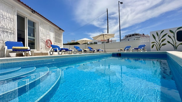 A swimming pool with blue tiles, surrounded by lounge chairs and umbrellas. - Rosa | Private Pool | Sleeps 8 | Albufeira (Albufeira)