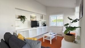 A living room with a sofa, coffee table, TV, and plants. - Rosa | Private Pool | Sleeps 8 | Albufeira (Albufeira)
