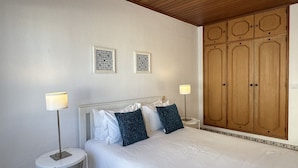 A bedroom with a bed, two bedside tables, two wall-mounted lamps, a large wooden wardrobe, and two framed wall decorations. - Rosa | Private Pool | Sleeps 8 | Albufeira (Albufeira)