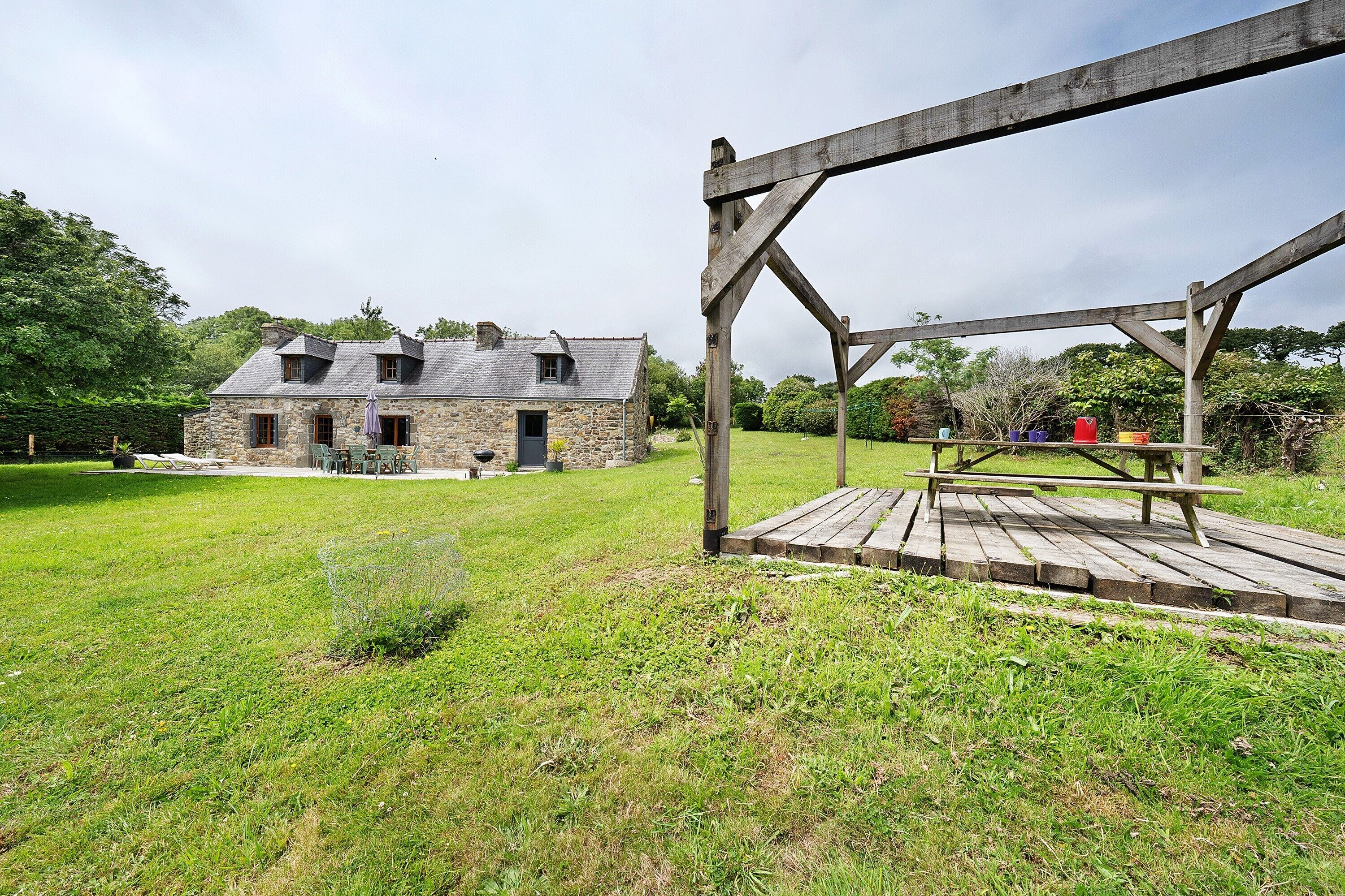 A stone house with a wooden deck and picnic table.