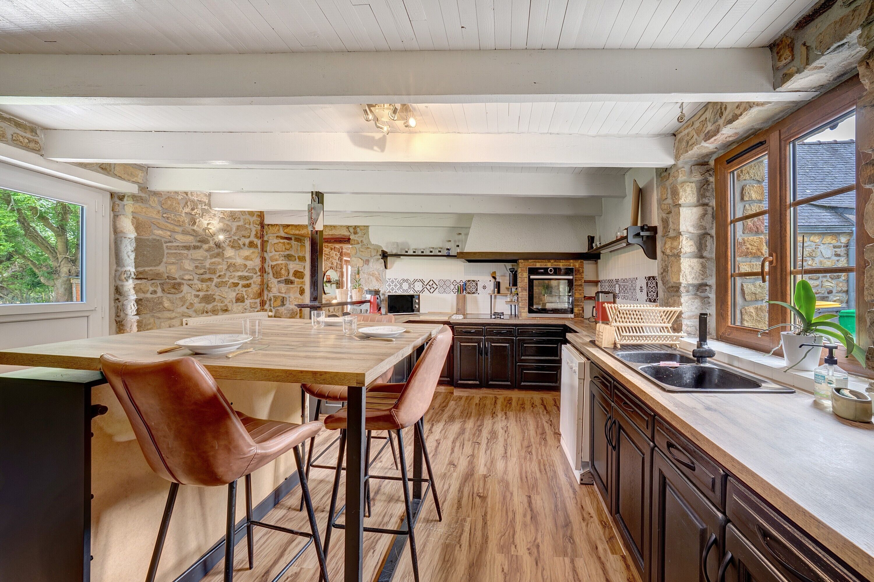A kitchen with a wooden island, stone walls, and a view of the outdoors.
