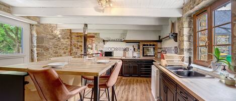 A kitchen with a wooden island, stone walls, and a view of the outdoors.