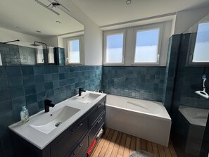 A modern bathroom with two sinks, a bathtub, and a large mirror.
