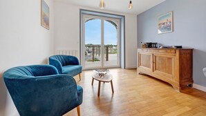 Ein modernes Wohnzimmer mit einer Couch, einem Holzkabinett und einer Glastür zum Außenbalkon.