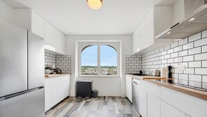 Eine moderne Küche mit weißen Schränken, einem Fenster mit Ausblick und einem Fischgrätparkettboden.