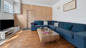 A living room with a sectional sofa, a flat-screen TV, a coffee table, and wooden flooring. - Family Home in Morgat, Enclosed Garden, 2 Minutes from the Beach (Crozon)