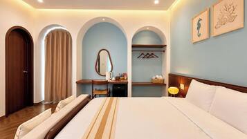 A hotel room with a large bed, a desk, a chair, a mirror, and a wardrobe.