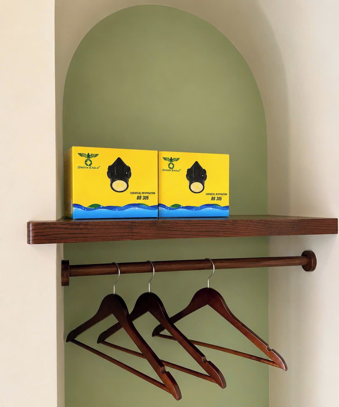 A shelf with two boxes of Green Eagle chemical respirators and a wooden hanger rod with hangers.