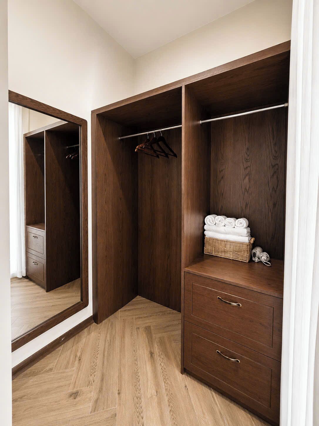 Un armario con puertas de madera, una percha y una cesta de mimbre sobre un tocador.