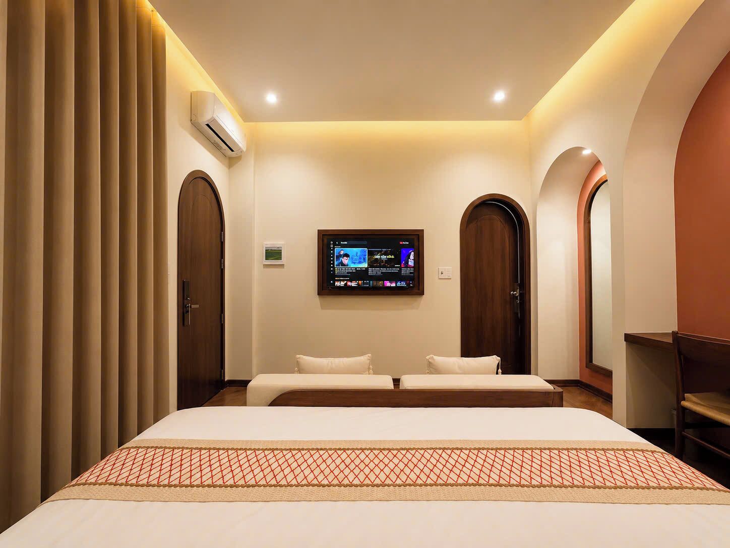 Een hotelkamer met een groot bed, een flatscreen televisie aan de muur en twee deuren.