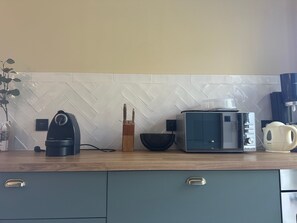 Una cucina con macchina da caffè, tostapane, bollitore e un set di coltelli.