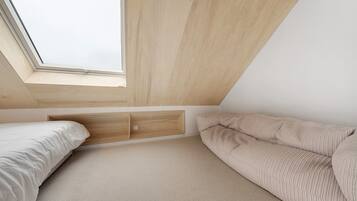 Une chambre dotée d’une lucarne, d’un lit, d’un canapé et d’un meuble de rangement intégré.