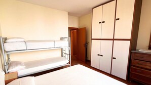 Um quarto com uma cama de solteiro, um guarda-roupa e uma cômoda.