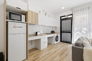 A compact kitchen with a microwave, toaster, sink, and washing machine.