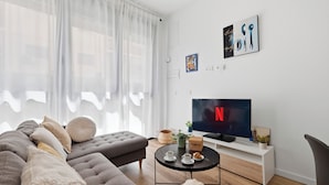 Ein modernes Wohnzimmer mit einer Couch, einem Couchtisch, einem Fernseher und Kunstwerken an der Wand.