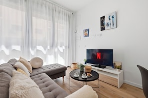 A modern living room with a sofa, a coffee table, a TV, and artwork on the wall.