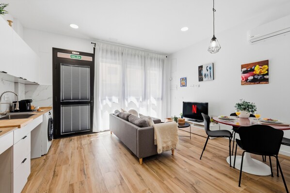 A modern living space with a sofa, dining table, and kitchen area. - Bright Loft | Fully Equipped | Smart TV | AC | Sleeps 2 (Torrefiel)