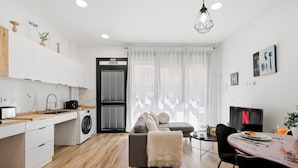 Eine moderne Küche mit Waschmaschine, ein Essbereich mit Tisch und Stühlen sowie ein Wohnbereich mit Sofa.