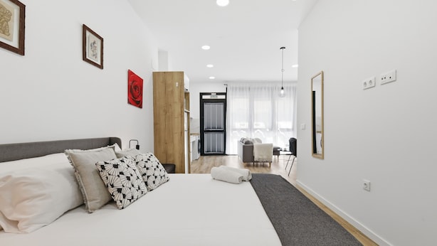 Ein modernes Hotelzimmer mit einem großen Bett, einer Wandpaneele aus Holz, einem Essbereich und Blick auf die Stadt.