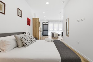 Une chambre d’hôtel moderne dotée d’un grand lit, d’un mur décoratif en bois, d’un coin repas et offrant une vue sur la ville.