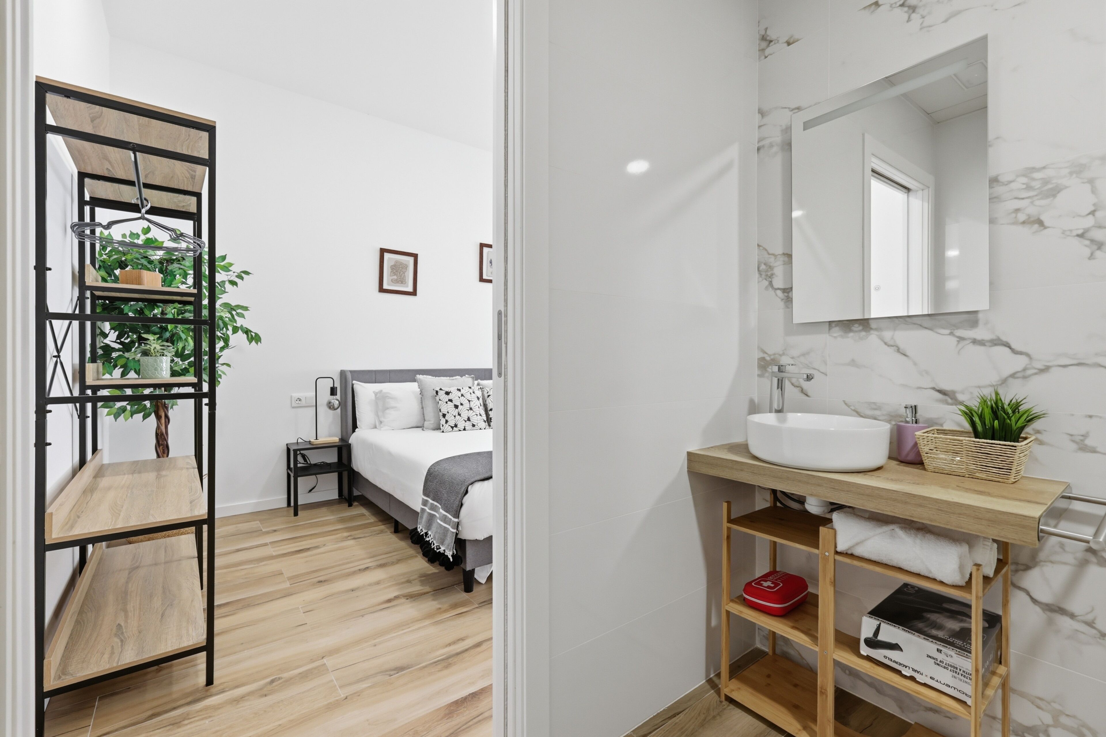 Een moderne badkamer met een marmeren wastafel, een houten opbergmeubel en een spiegel.