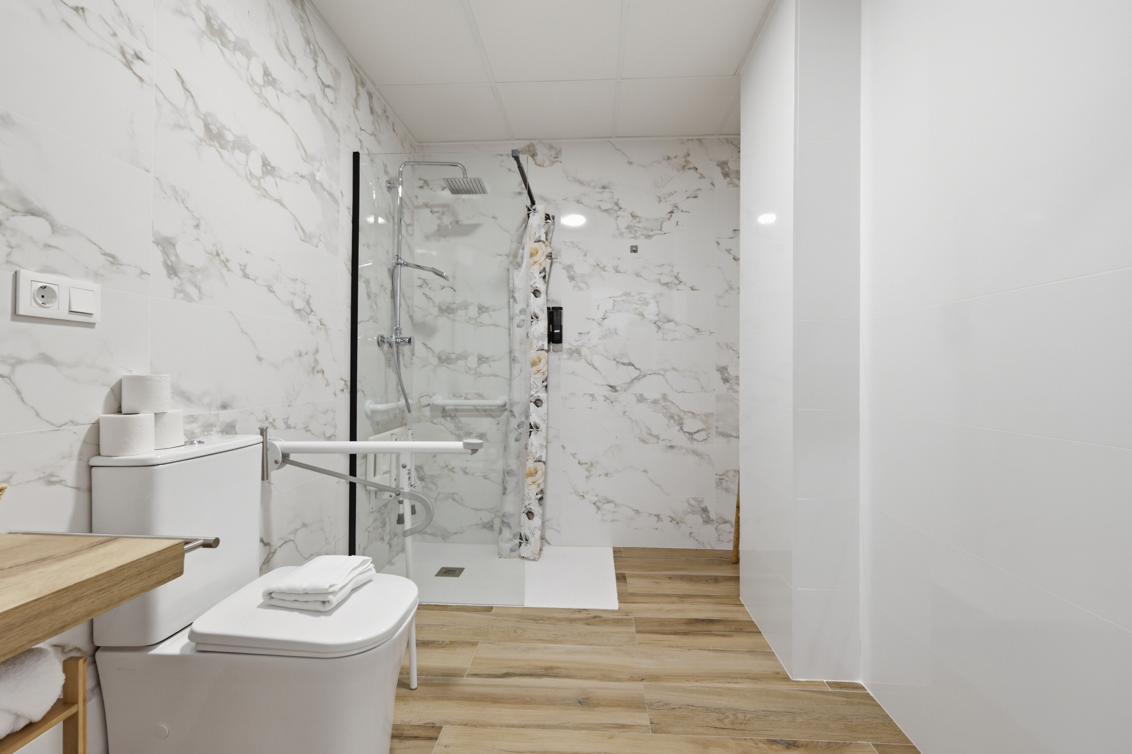 Un baño moderno con inodoro, ducha y paredes de mármol.