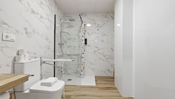 Un baño moderno con inodoro, ducha y paredes de mármol.