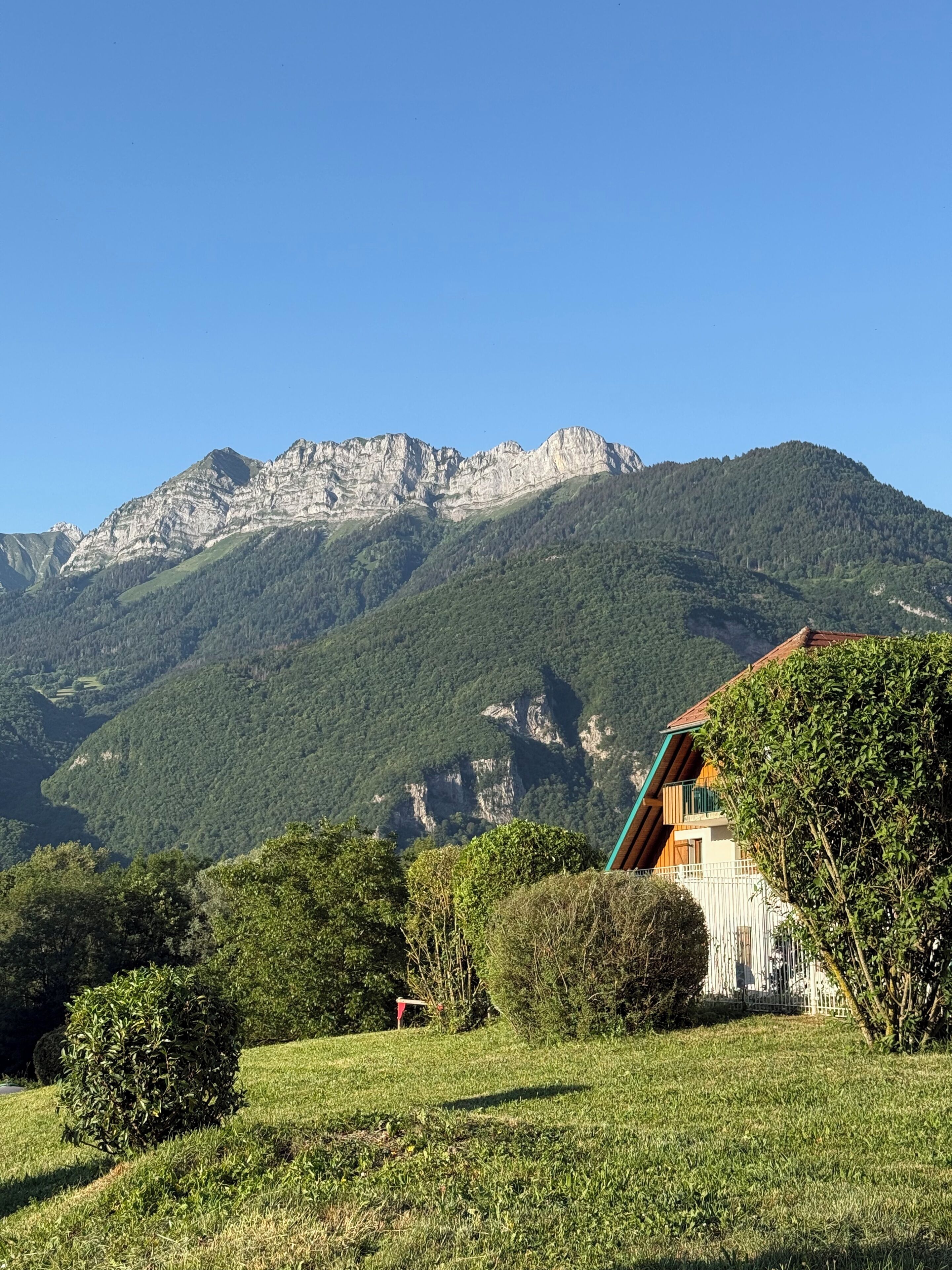 A mountain landscape with a house featuring a balcony and a view of the mountains.