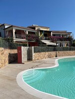 Una propiedad residencial con piscina, paredes de piedra y un balcón con barandilla.