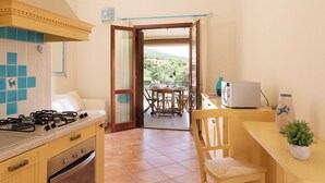 A kitchen with a gas stove, oven, and a dining area with a table and chairs. - Casa Luna e Sole by Wonderful Italy (Maiorca)