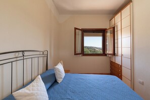 Een slaapkamer met een bed, een raam en een inloopkast.