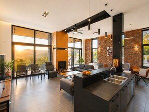 A modern kitchen with a central island, large windows, and a fireplace. - Luxury Hillside Villa with Pool, Terraces & Stunning Views (Gorno Sonje)