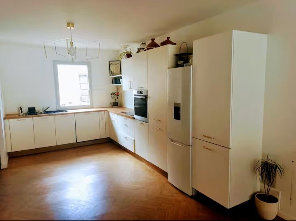 A kitchen with white cabinets, a countertop, a built-in oven, and a potted plant.